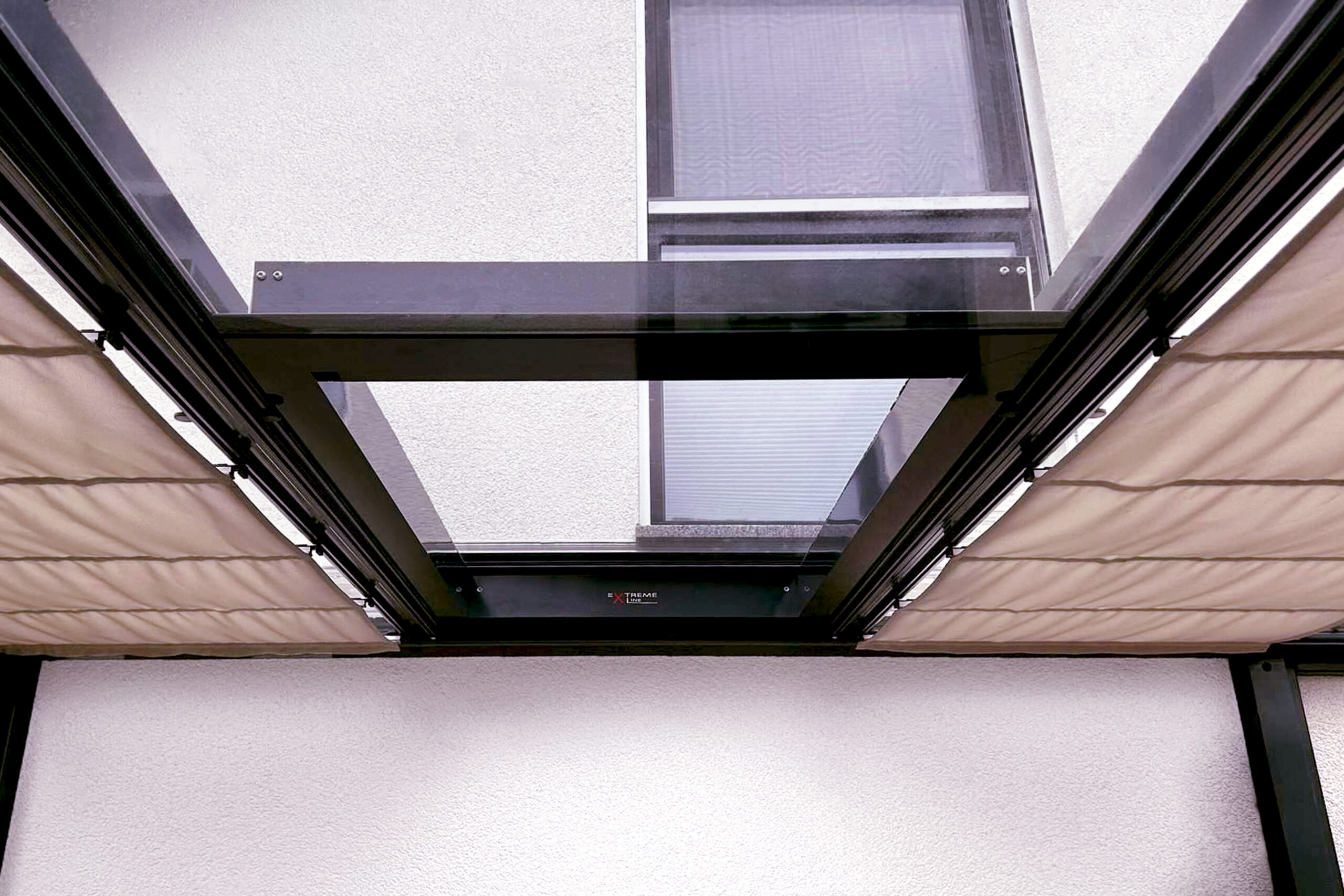 Glas-Schiebeelement in einer modernen Terrassenüberdachung mit seitlicher Beschattung. Das verschiebbare Glaselement bietet flexiblen Wind- und Wetterschutz für Terrasse, Wintergarten oder Outdoor-Lounge und sorgt gleichzeitig für maximale Transparenz und Lichteinfall.