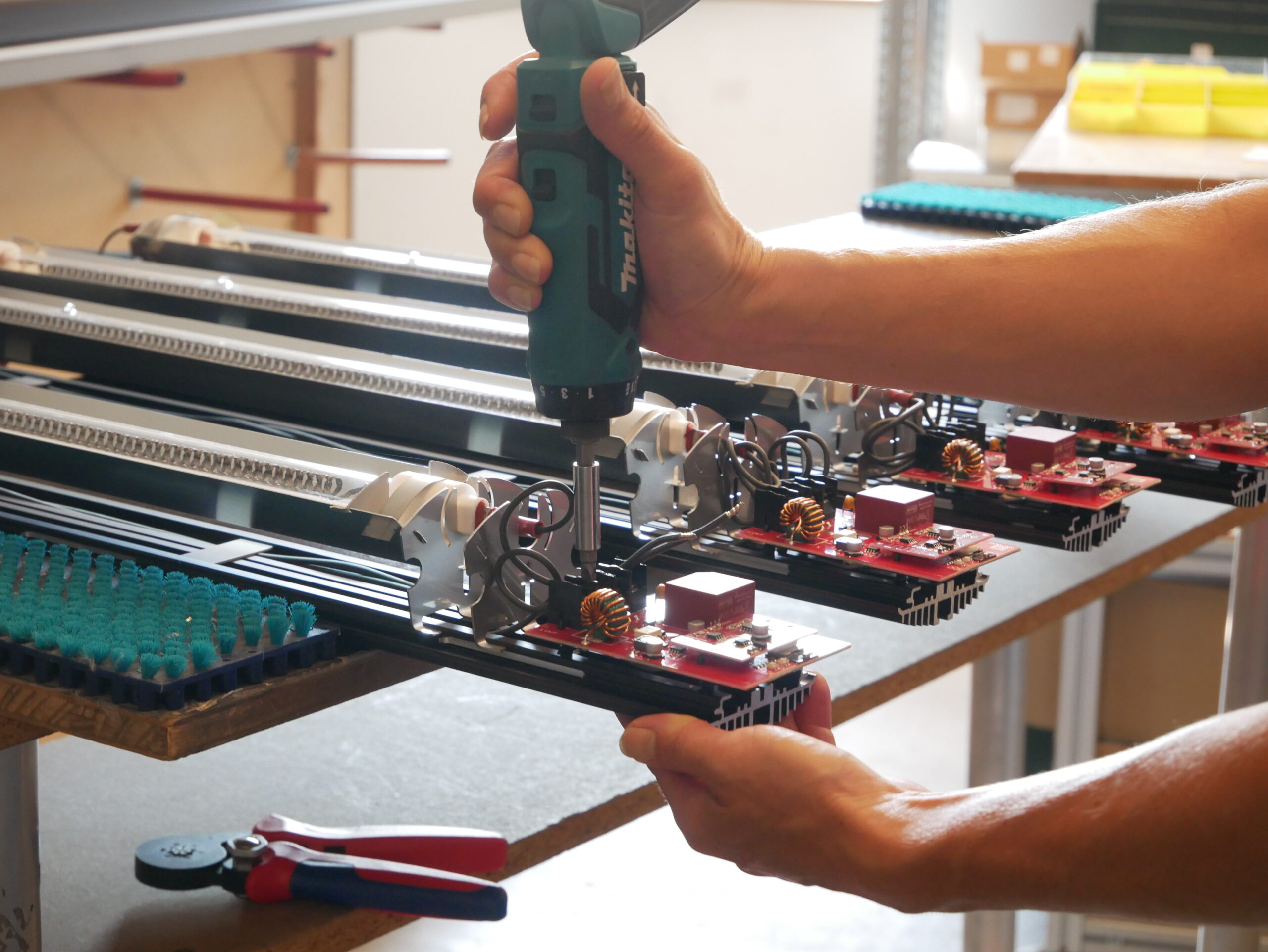Montage eines Infrarot-Heizstrahlers in der Produktion. Ein Mitarbeiter in Halfing beim Chiemsee installiert elektronische Komponenten und Heiztechnik in einem hochwertigen Heizsystem für Terrassen, Wintergärten, Gastronomie und industrielle Anwendungen.