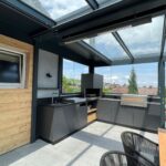 Eine Outdoor Küchen in einem Sommergarten mit integrierten Grill und eienr gemütlichen Sitzgruppe