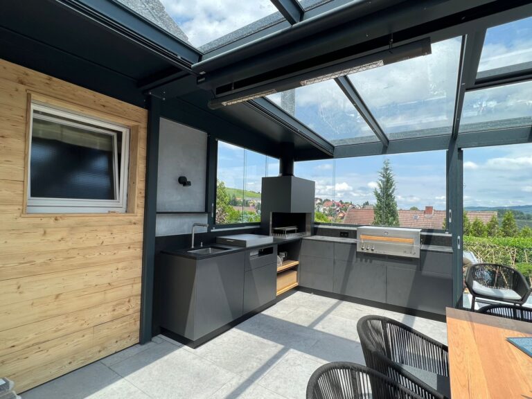 Eine Outdoor Küchen in einem Sommergarten mit integrierten Grill und eienr gemütlichen Sitzgruppe