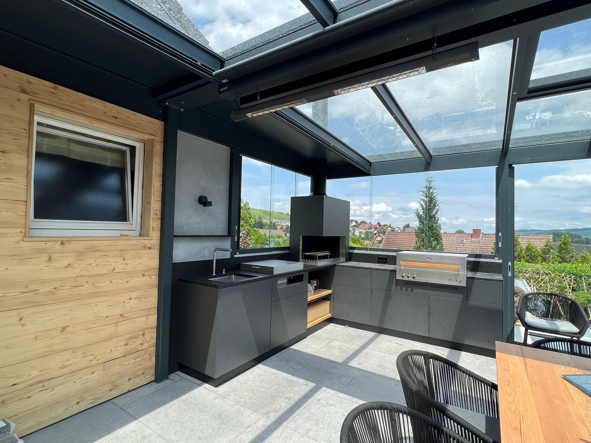 Eine Outdoor Küchen in einem Sommergarten mit integrierten Grill und eienr gemütlichen Sitzgruppe